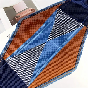 Détail d'un foulard carré plissé avec motif pied-de-poule et blocs de couleurs