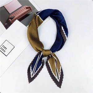 Détail d'un foulard plissé à rayures bleu marine et jaune moutarde sur fond blanc