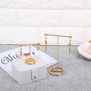 Golden T-bar metal jewelry display stands for earrings on minimalist grey linen table