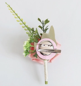 Détail de la boutonnière rose avec épingle en métal et poignée entourée de ruban blanc