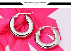 Macro shot of polished silver stainless steel hoop earrings on pink ribbon background