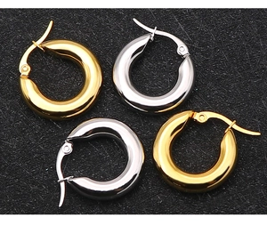 Close-up of polished thick hoop earrings in gold and silver finishes on black background