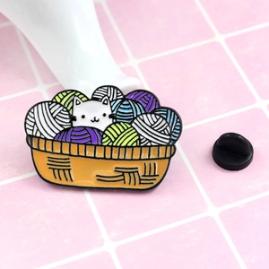 Close-up of a cute cat and colorful yarn ball enamel pin with a black rubber clutch