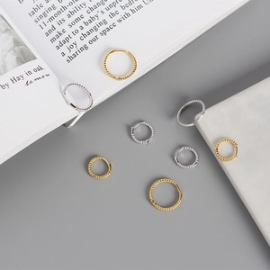 Macro shot of twisted rope hoop earrings in gold and silver finishes on a marble surface