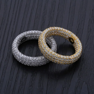 Close-up of gold and silver full zircon studded hip hop rings on a dark wooden background