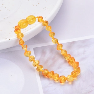Natural Baltic amber baby bracelet with irregular beads on white ceramic plate