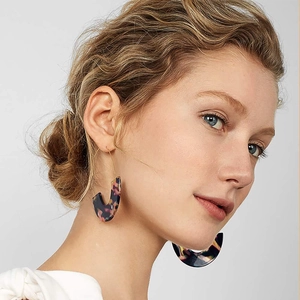 Close-up of geometric U-shaped earrings with colorful tortoiseshell texture on female model