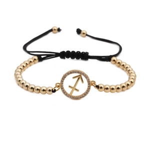 Detailed shot of Sagittarius zodiac charm with white zircon and gold beaded woven bracelet