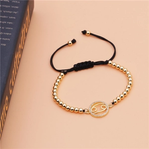 Detail of Cancer zodiac charm with micro-pave crystals on black adjustable bracelet