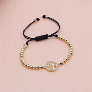Close-up of Capricorn zodiac charm on adjustable gold beaded woven bracelet