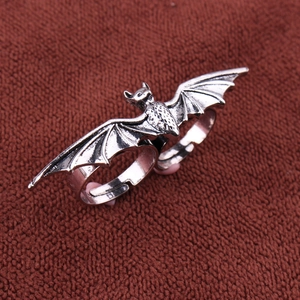 Macro shot of double finger bat wing ring in antique silver finish on red fabric