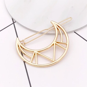 Minimalist gold crescent moon hair clip with geometric hollow design on marble surface