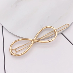 Detail shot of a minimalist gold infinity symbol hair clip on a marble surface