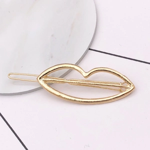 Detail of a minimalist gold hollow lip-shaped hair clip on a marble display piece