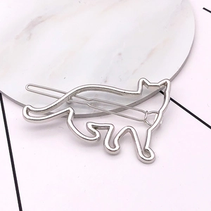 Detailed close-up of a silver metal cat-shaped hair clip on a marble surface