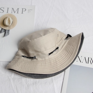 Detailed macro view of beige canvas bucket hat with metal eyelets and SPORT cord