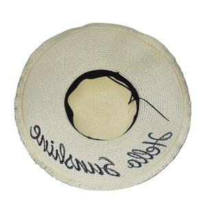Detail of beige straw hat with Hello Sunshine embroidery and frayed fringe brim edge