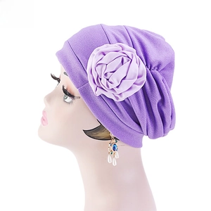 Détail du turban plissé violet avec une grande décoration de rose en tissu doux