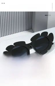 Detailed view of black daisy-shaped sunglasses displayed on a minimalist geometric pedestal