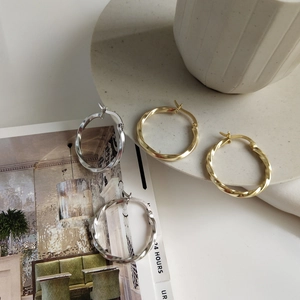 Macro shot of twisted sterling silver hoop earrings in gold and silver on a tray