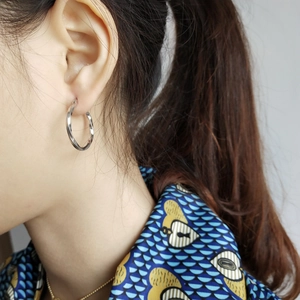 Detailed view of silver twisted hoop earrings worn by a model to show elegant style