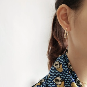Detail of twisted gold hoop earrings in 925 sterling silver worn by a model