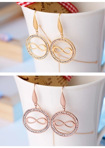 Détails de boucles d'oreilles or et or rose avec cercles de cristal et signes infini