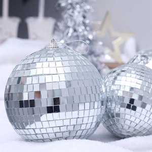 Silver disco mirror ball ornaments with hanging strings on white plush holiday background