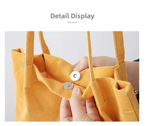 Detail view of the yellow corduroy tote bag showing the magnetic snap button closure