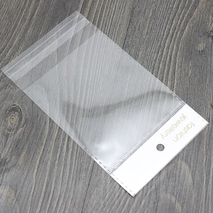 Klare selbstklebende Schmuckverpackungen mit weißem Karton auf Holzdekor