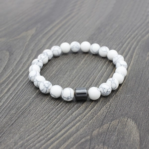 Detail of white turquoise beaded bracelet with grey cylinder bead on dark wood surface