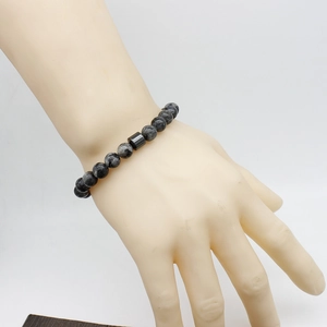 Close-up of natural black stone and tiger eye beaded bracelet worn on a wrist