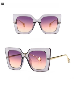 Detail view of cat eye sunglasses with grey frame and purple pink gradient lenses
