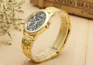 Détail de la montre Geneva dorée avec cadran noir et chiffres romains sur fond en bois naturel