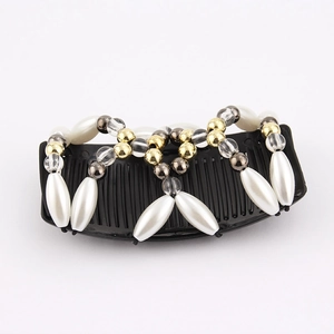 Detail of magic hair comb with white faux pearls and gold beads on black plastic teeth