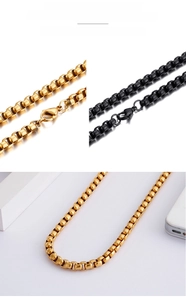 Detail of square box chain necklace in gold and black steel with lobster clasp