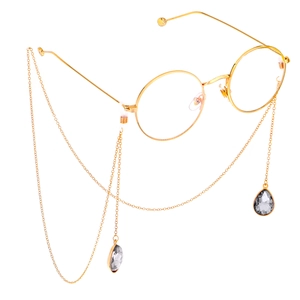Detail view of golden metal round glasses with teardrop crystal pendant chain