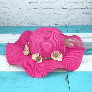 Fuchsia straw sun hat with decorative floral wreath and ribbon for summer beach vacation