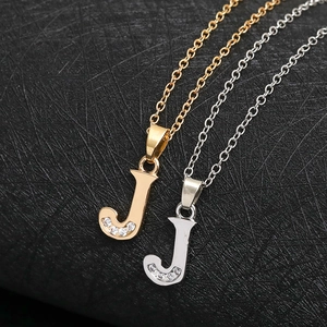 Macro shot of letter J pendant necklace in gold and silver finish with crystal inlay