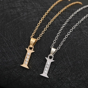 Close-up of gold and silver letter I pendants with four inlaid white zircons on black background
