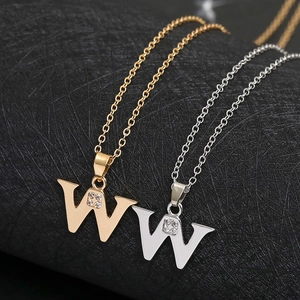 Macro shot of gold and silver letter W pendants with clear cubic zirconia on link chains