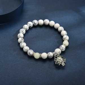White turquoise yoga bracelet with luminous lotus pendant on dark blue background