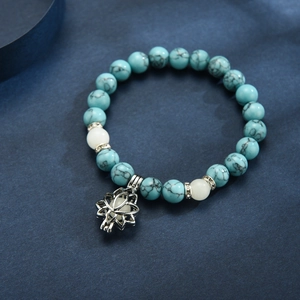 Detail of turquoise bead yoga bracelet with glowing lotus pendant and rhinestone accents