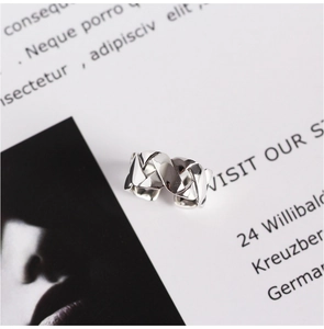 Detailed close-up of woven texture and crossover design on silver open ring band