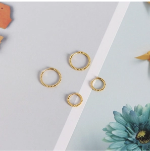 Detailed view of gold twisted rope hoop earrings set with minimalist daisy decor