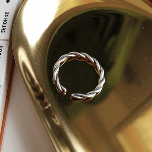 Close-up of a two-tone twisted rope silver ring on a golden tray with an open-end design