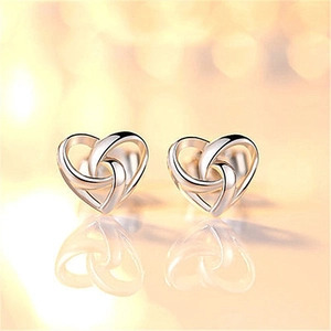 Macro shot of silver heart stud earrings featuring a hollow woven metal texture