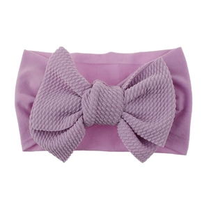 Detailed close-up of a purple nylon baby headband with a large textured knit bow