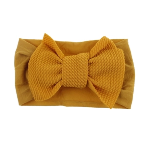 Detail of ginger yellow waffle texture bow on a soft elastic nylon baby headband
