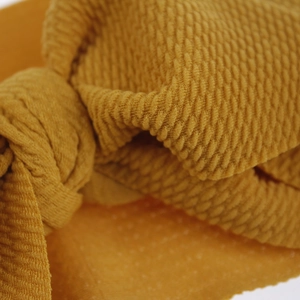 Macro view showing the intricate bubble texture of a mustard yellow baby headband